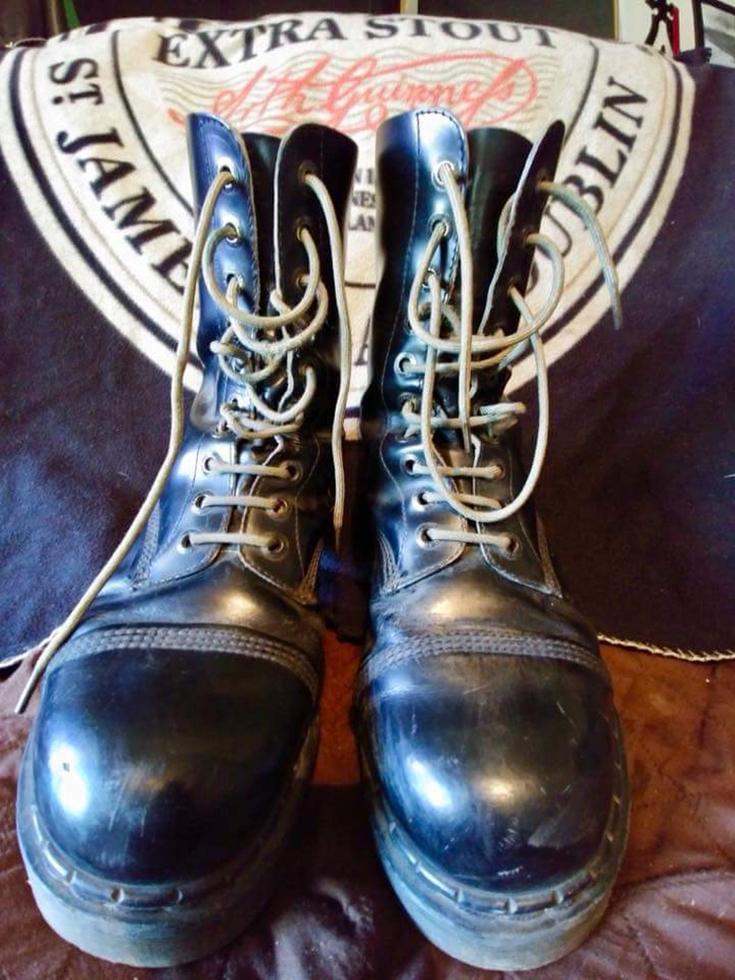 Filling the frame, a pair of worn government-issue combat boots with thick while laces. The toes of the boots are almost comically large, they're so close to the lens.