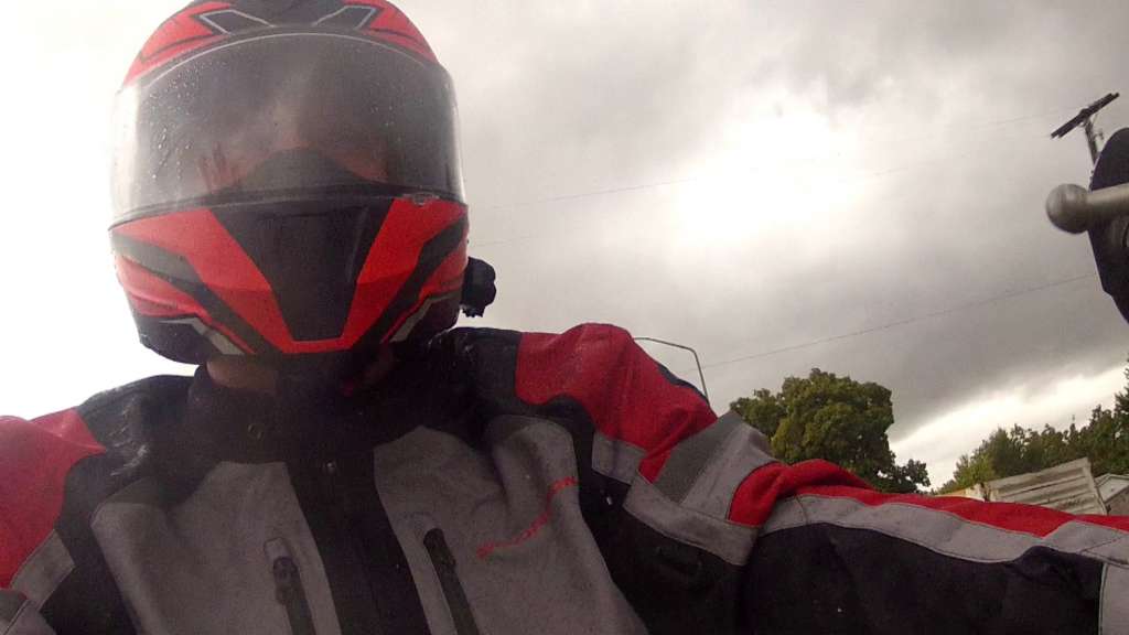 Reviewer wearing the Optima Jacket in heavy rainfall and cloudy skies