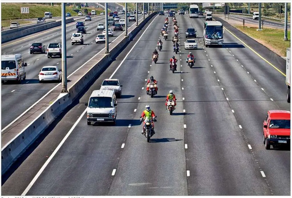 22 Motorcycle riders dressed like Santa Clause wearing helmets ride in staggered formation on a 5 lane freeway