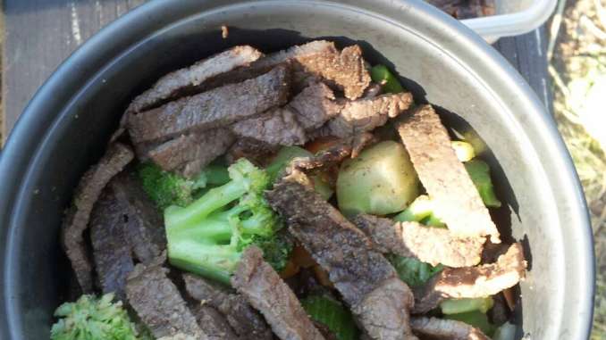The mess kit crock is filled with bright green diced broccoli and mixed veggies with strips of sauteed steak.