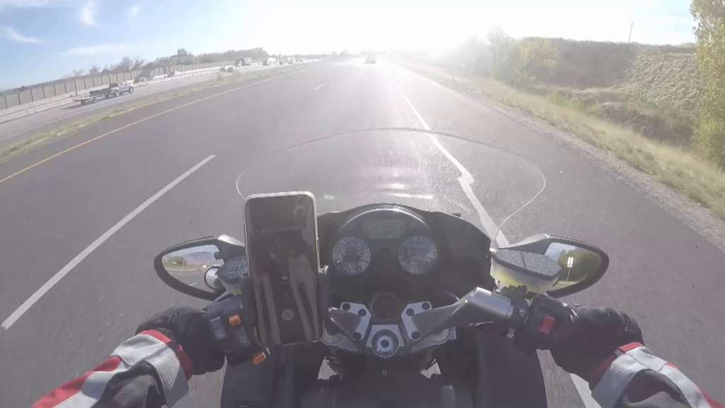 The view from the cockpit of a motorcycle. A cell phone mounted to the bars shows an incoming call.