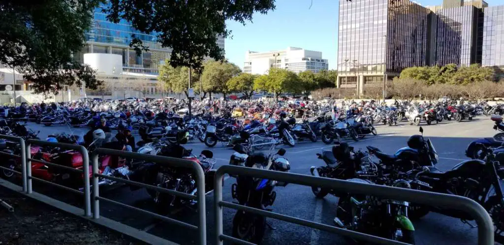 Pictures is hundreds on bikes arrayed in a wide, bright parking lot.