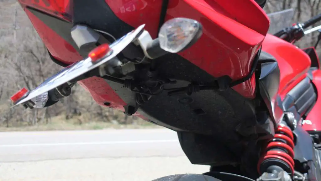 A close up of the underside of a 2012 Kawasaki Ninja 650, with the Viking Sport Tail Bag mounted. Bungee cords criss-cross beneath the tail piece.