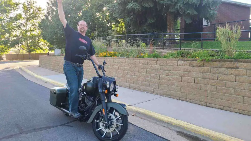 TMW Staff Writer Eric Leaverton posed standing on the right side floorboard of the Spring Dark Horse while the bike rests on it's side stand. Picture showcases the excellent balance of the bike.