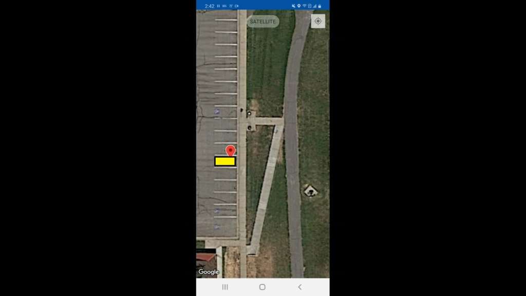 Pictured is a screen grab from the Monimoto app, showing a GPS tag in Google Maps "satellite" view. The parking stall at the tag location is highlighted in yellow.