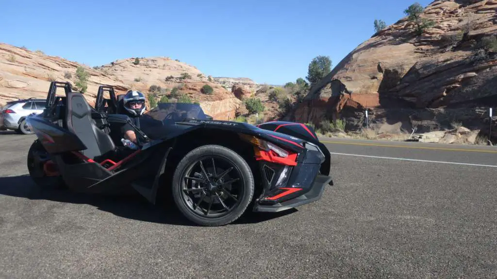 From TMW's Slingshot R review series, the Slingshot R sits imposingly in a roadside pullout, picturesque rock formations in the background.