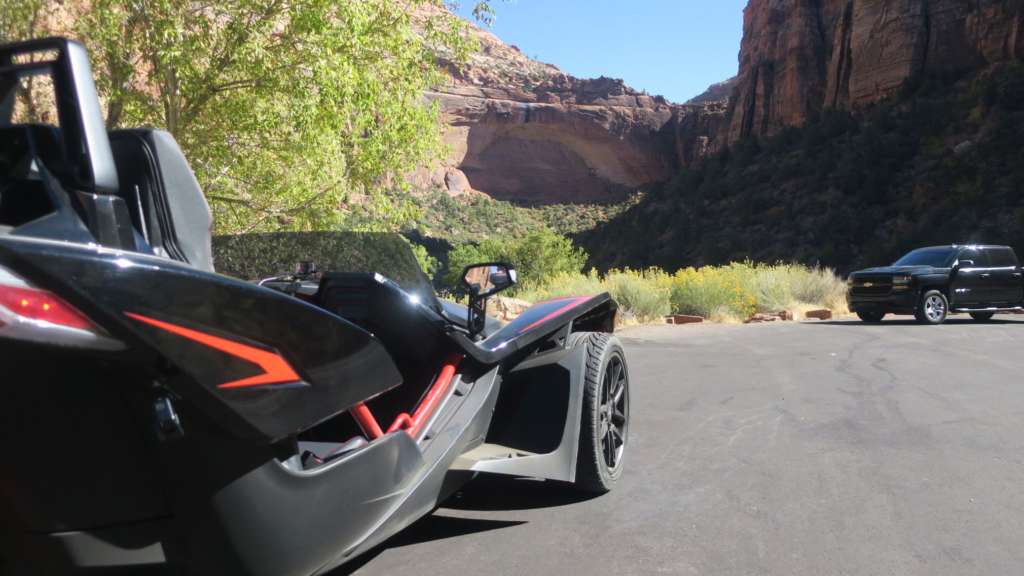 The passenger side of the Slingshot R from a low angle. In the background, immense rock formations from Utah's Zions National Park.